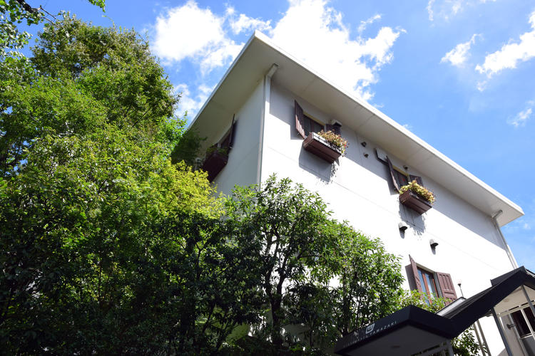 緑に囲まれた洋風の建物2階店舗